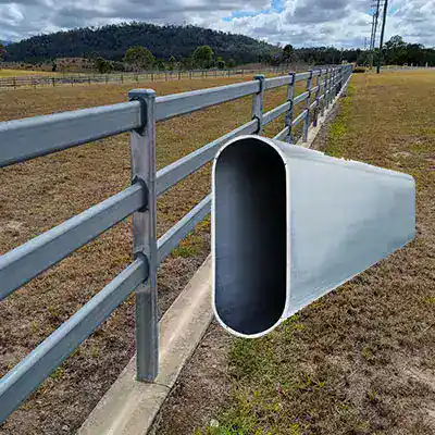 Cattle-rail - Stock Fence Australia | High Quality - Hot Dip Gal Cattle Station Fencing Metal fence in a rural field with a large oval-shaped metal tube protruding through the fence.